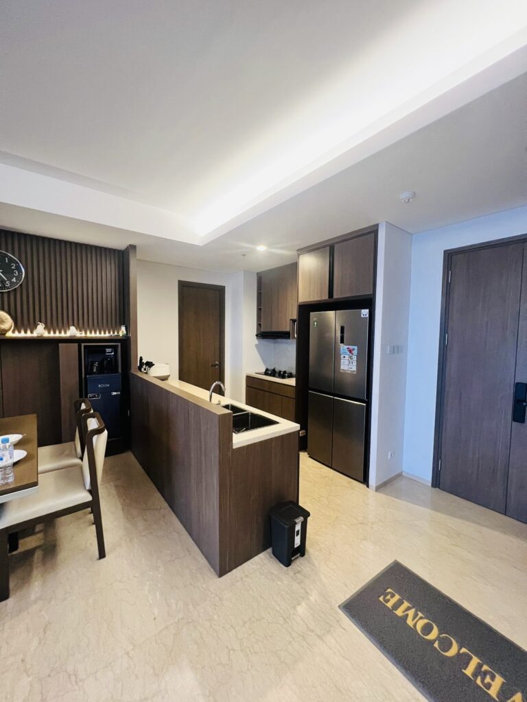 Pemandangan area dapur, pantry, dan ruang makan dari dekat pintu masuk apartemen 31 Sudirman Suites Makassar.