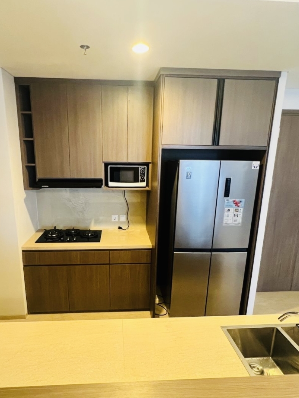 Dapur lengkap dengan kompor tanam, microwave, dan kulkas 4 pintu di apartemen 31 Sudirman Suites Makassar.