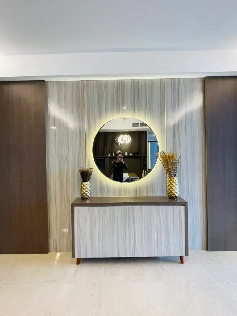 Foyer mewah di apartemen 31 Sudirman Suites Makassar dengan cermin bulat berlampu dan credenza, bagian dari unit 3 kamar + 1 yang dijual.