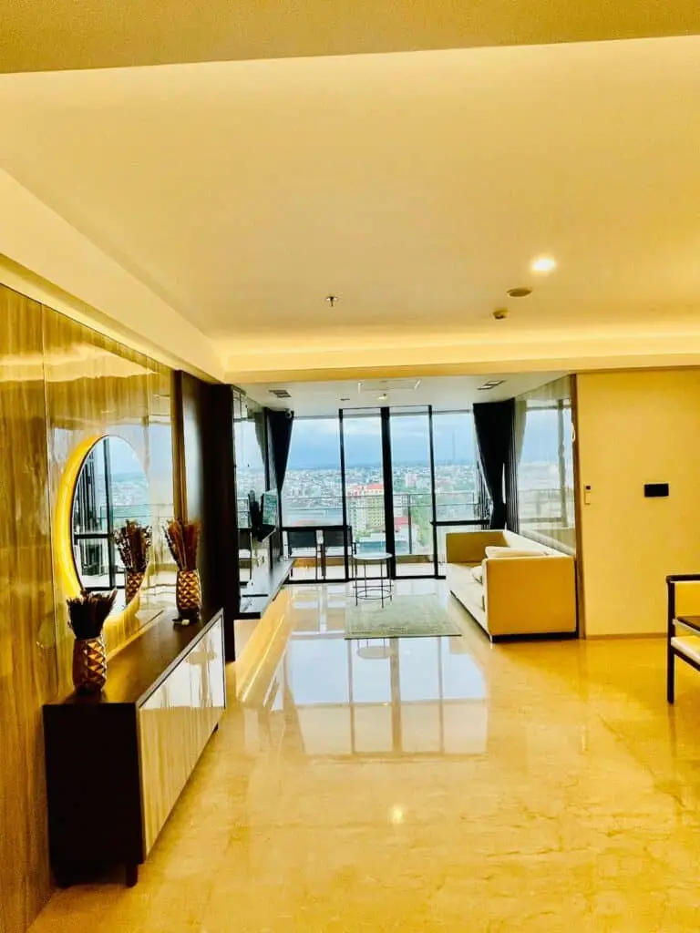 Interior ruang tamu yang luas dengan lantai marmer berkilau dan jendela besar di apartemen 31 Sudirman Suites Makassar 3 kamar + 1.