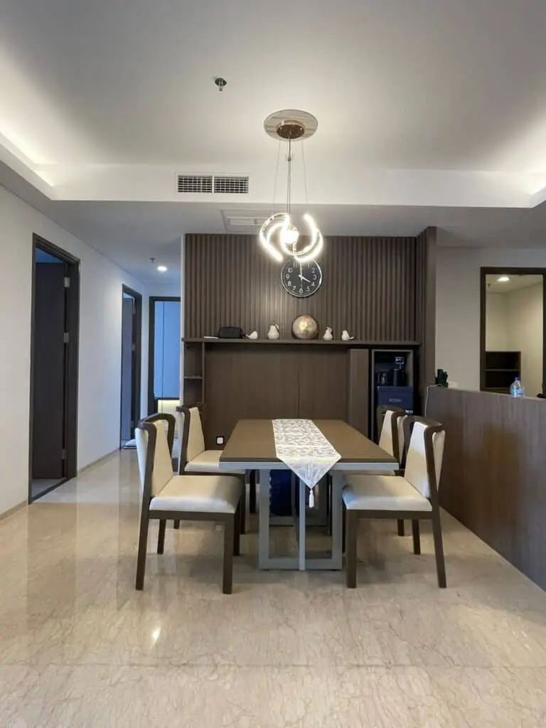 Area ruang makan yang elegan dengan meja untuk 4 orang dan lampu gantung modern di dalam unit apartemen 31 Sudirman Suites Makassar.