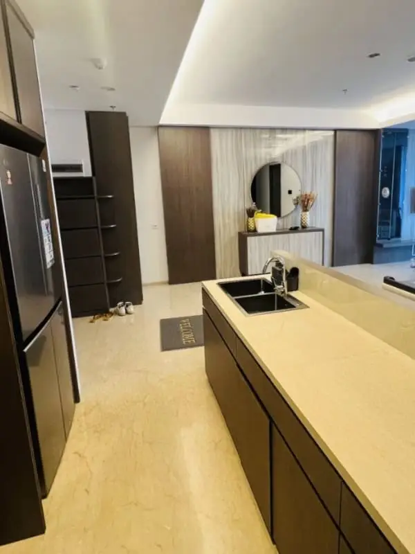 Area dapur kering yang bersih dan modern dengan kulkas dua pintu di apartemen 31 Sudirman Suites Makassar unit 3 kamar + 1.