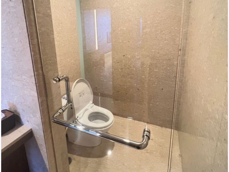 Toilet modern dengan partisi kaca dan dinding marmer di kamar mandi apartemen 31 Sudirman Suites Makassar, bagian dari unit 3 kamar + 1 yang dijual.